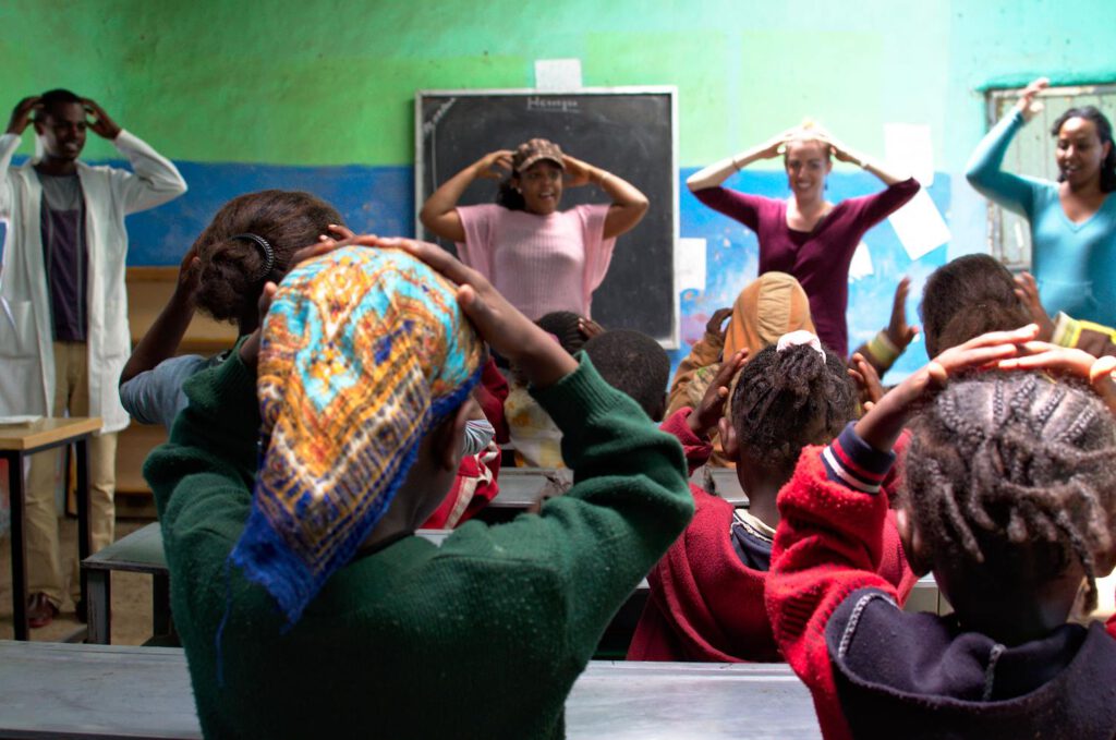 Volunteers dance with children in classroom
